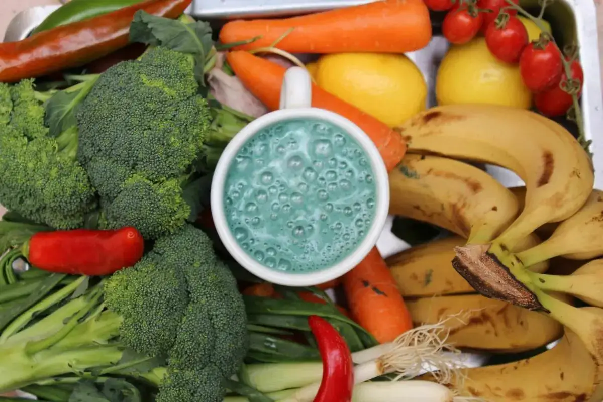 a cup of blue liquid surrounded by vegetables