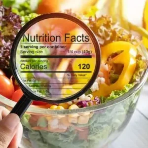 Nutritional Information Concept. Hand Use The Magnifying Glass To Zoom In To See The Details Of The Nutrition Facts From Food , Salad Bowl